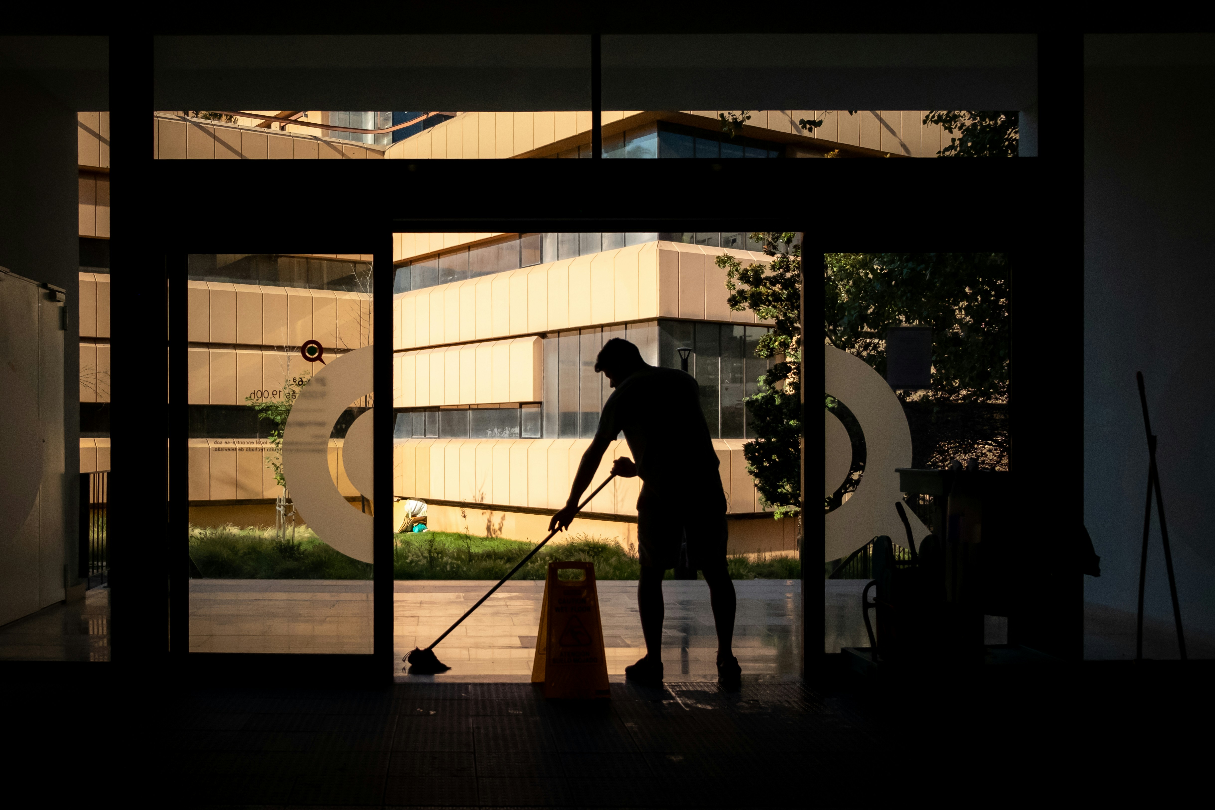 Janitor mopping a commercial building lobby at sunset
